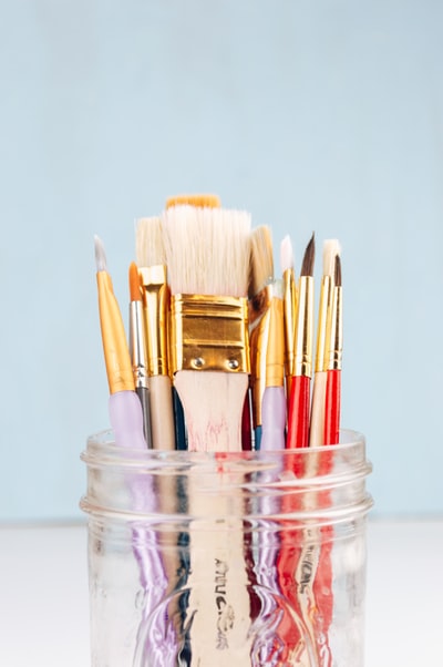 Brown and red makeup brush in a transparent glass jar
